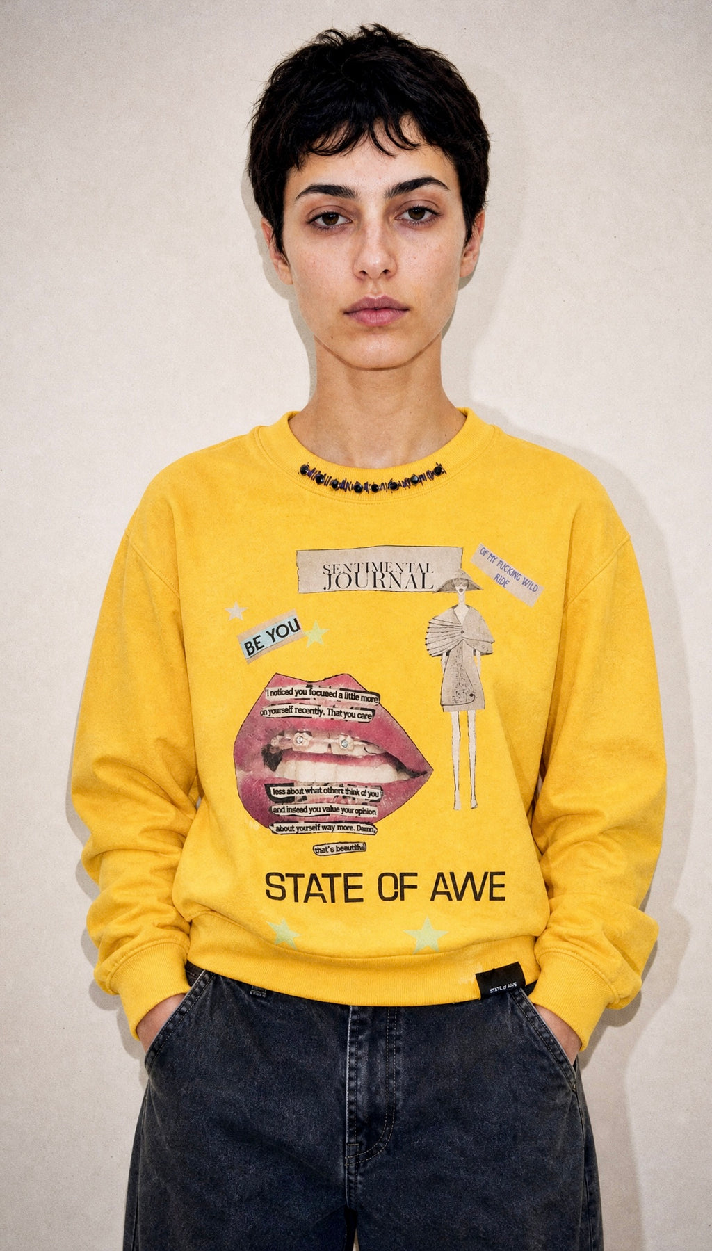 Model wearing the Sentimental Journey sweatshirt, front view, showing the graphic collage print with pink lips illustration and 'STATE OF AWE' text.